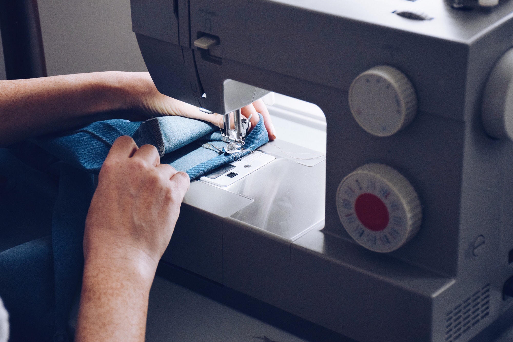 seamstress is hemming jeans on sewing machine
